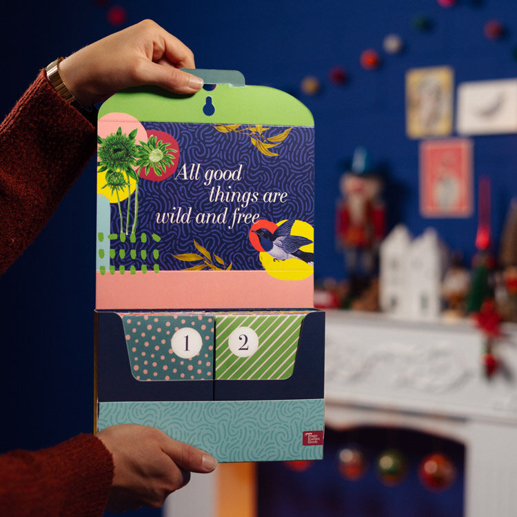 Geöffneter Saatgut-Adventskalender „Gemüse, Kräuter & Blumen“ mit den Tütchen 1 und 2, in Händen gehalten